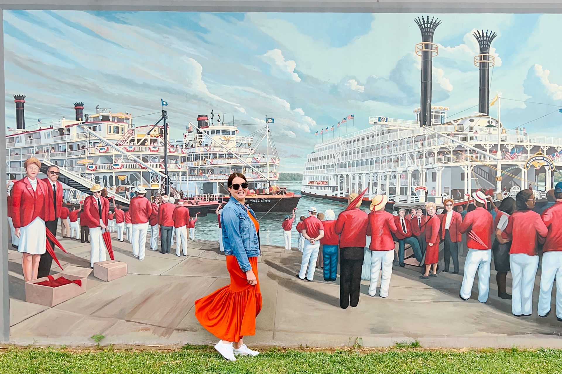 A photo of a woman standing in from of the painted murals on the wall of the Paducah riverfront.