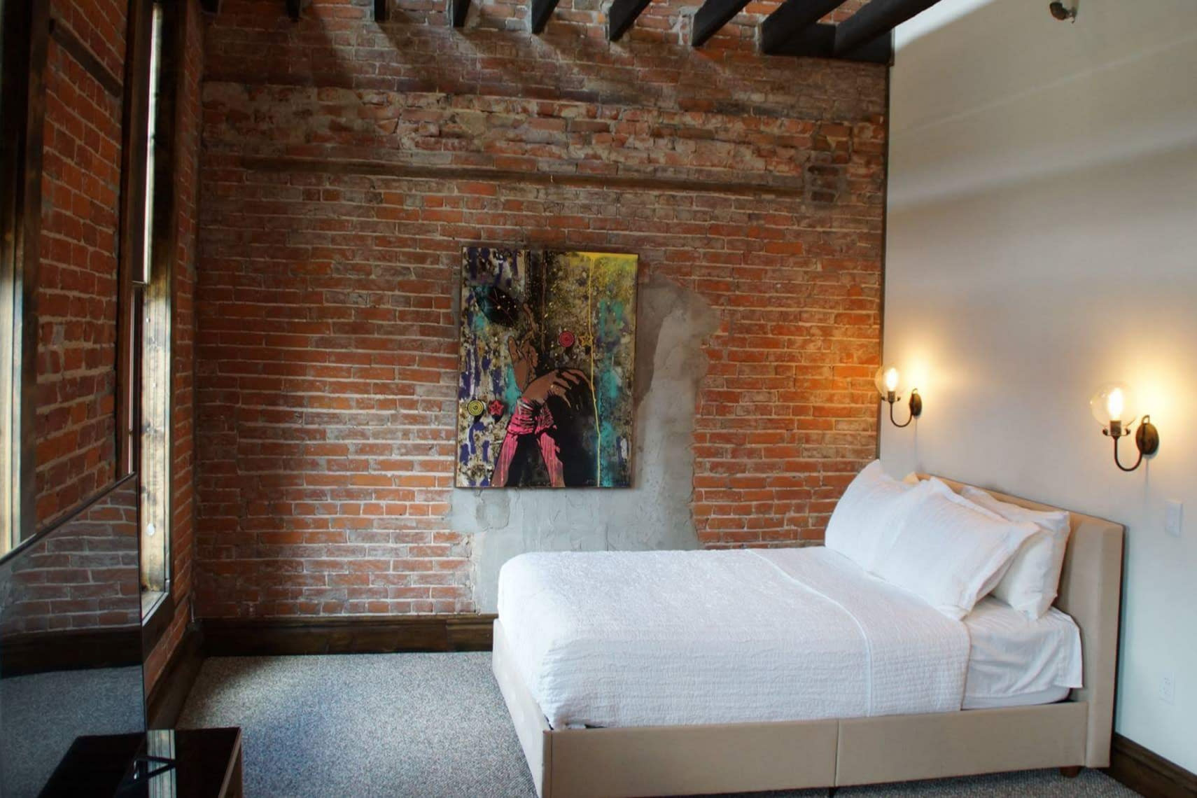 A comfy white bed in a room with exposed brick in downtown Paducah, KY